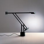 Artemide Tizio table lamp in black, articulated counterbalanced arms with small pivoting head and wedge counterweights on a cylindrical base, side view.