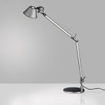 Artemide Tolomeo Classic table lamp in polished aluminum, articulated counterweight arm with a conical metal shade on a weighted circular tabletop base, three quarter view.