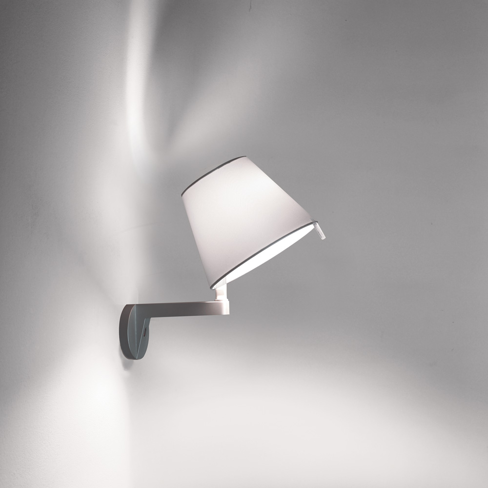 Artemide Melampo wall lamp in white, tilting fabric tapered shade on a slim arm extending from a small disc wall plate, three quarter view.