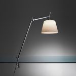 Artemide Tolomeo Mega table lamp in polished aluminum with parchment shade, large articulated arm extended over an edge clamp mount, three quarter side view.