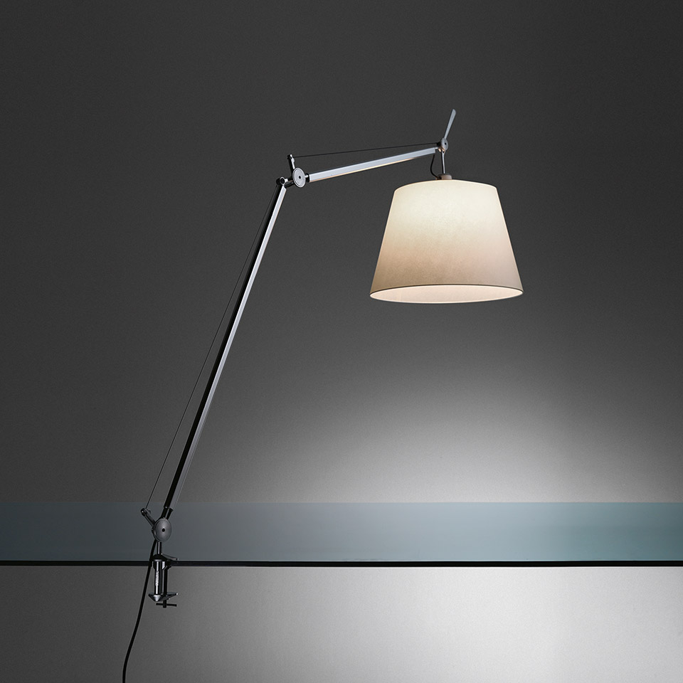 Artemide Tolomeo Mega table lamp in polished aluminum with parchment shade, large articulated arm extended over an edge clamp mount, three quarter side view.